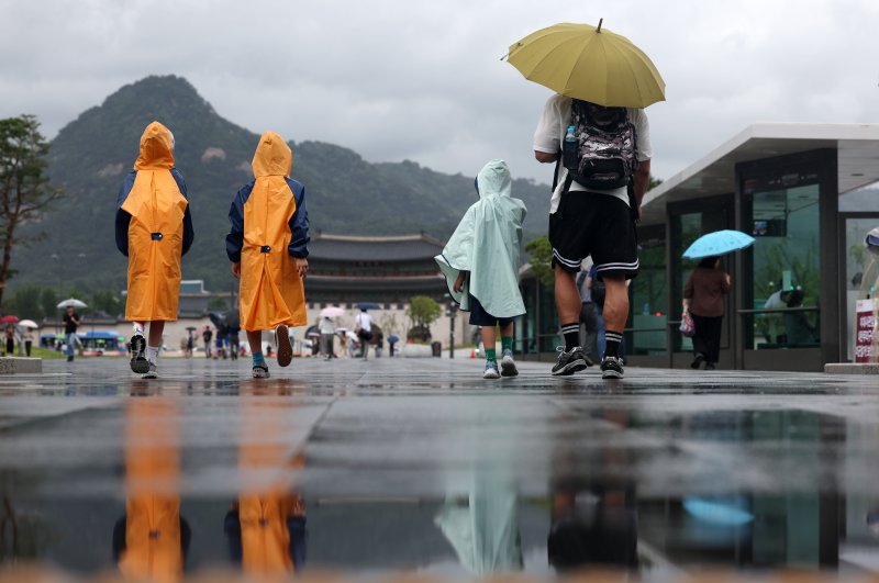 [서울=뉴시스] 조성우 기자 = 장마가 시작된 20일 오전 서울 광화문광장에서 우산과 비옷을 입은 한 가족이 이동하고 있다. 2025.06.20. xconfind@newsis.com /사진=뉴시스