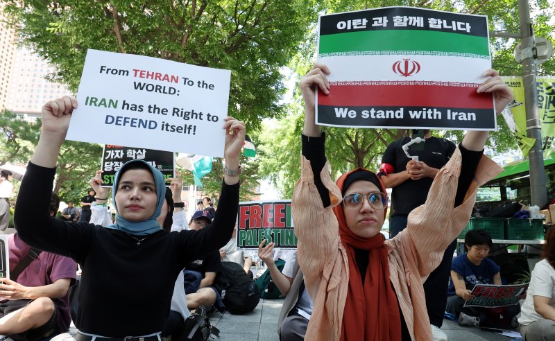 [서울=뉴시스] 추상철 기자 = 트럼프 미국 대통령이 이란의 주요 핵 시설을 파괴했다고 밝힌 22일 오후 서울 종로구 교보빌딩 인근에서 열린 노동자연대의 '전쟁 중단 및 이스라엘 공격 규탄집회'에서 이란인 집회 참가자가 피켓을 들고 전쟁 중단을 촉구하고 있다. scchoo@newsis.com 2025.06.23.