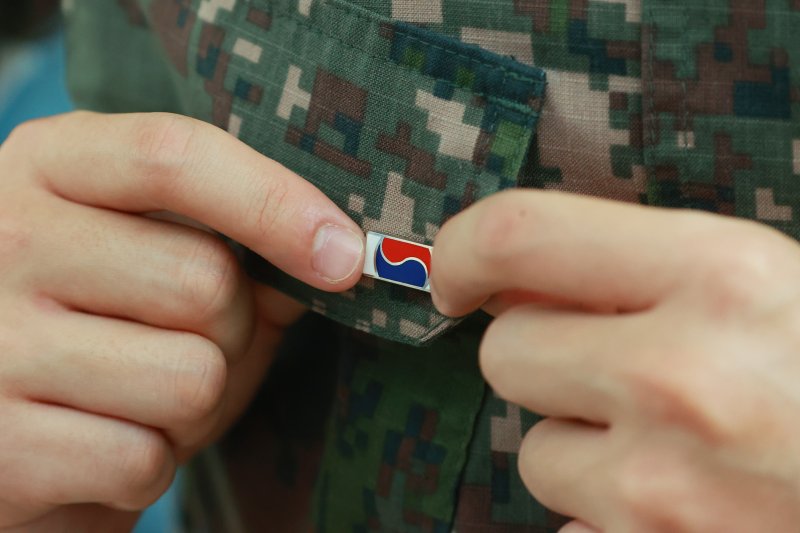 지난 6월 25일 서울 중구 서울역 대합실에 마련된 '121723 끝까지 찾아야 할 태극기' 캠페인 부스에서 군인이 태극기 배지를 패용하고 있다. 국가보훈부는 이날 서울역 대합실에서 6·25전쟁 75주년을 맞아 가족 품으로 돌아오지 못한 국군 전사자를 기리는 캠페인의 일환으로 한화의 K9 자주포 철로 12만 1천723개의 고유번호가 부여된 태극기 배지를 제작해 배포한다. 연합뉴스