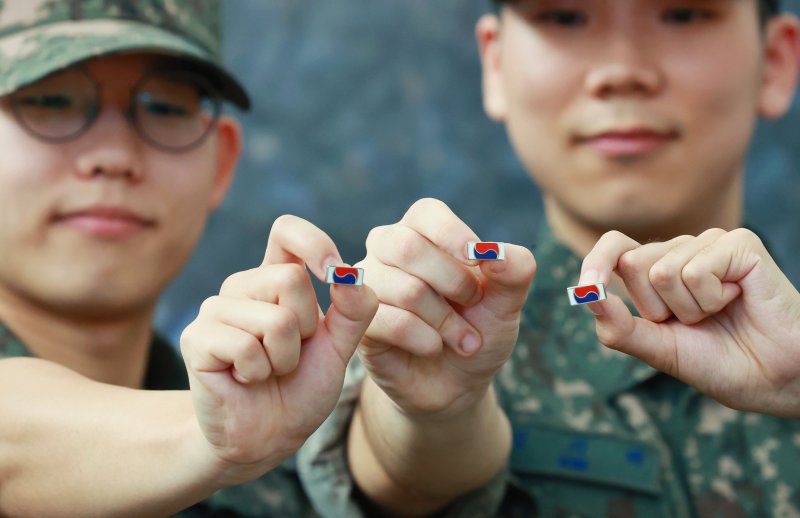 지난 6월 25일 서울 중구 서울역 대합실에 마련된 '121723 끝까지 찾아야 할 태극기' 캠페인 부스에서 군인들이 태극기를 들어보이고 있다. 국가보훈부는 이날 서울역 대합실에서 6·25전쟁 75주년을 맞아 가족 품으로 돌아오지 못한 국군 전사자를 기리는 캠페인의 일환으로 한화의 K9 자주포 철로 12만1723개의 고유번호가 부여된 태극기 배지를 제작해 배포한다. 연합뉴스