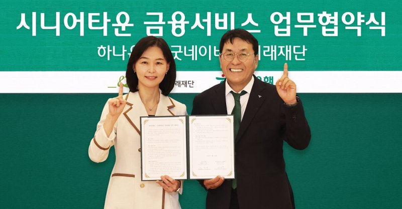 하나은행이 지난 25일 서울 을지로 하나은행 본점에서 굿네이버스 미래재단과 '시니어타운 사업 활성화 및 입주자 대상 금융 서비스 제공을 위한 업무협약'을 맺었다. 협약식에 참석한 김진우 하나은행 중앙영업그룹 부행장(오른쪽)이 양진옥 굿네이버스 미래재단 대표와 함께 업무협약서를 들고 기념 촬영을 하고 있다. 하나은행 제공.