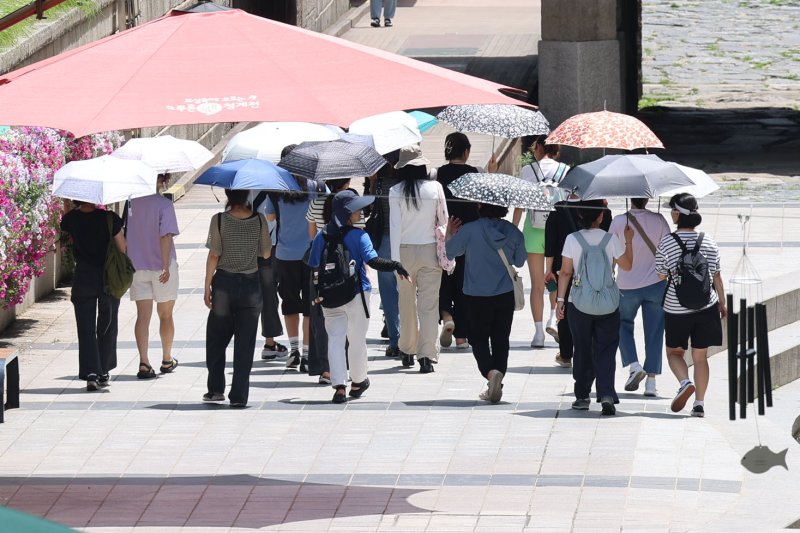 [서울=뉴시스] 권창회 기자 = 서울지역에 이틀째 폭염주의보가 지속중인 1일 서울 중구 청계천 인근에서 시민들이 양산을 쓰고 이동하고 있다. 2025.07.01. kch0523@newsis.com
