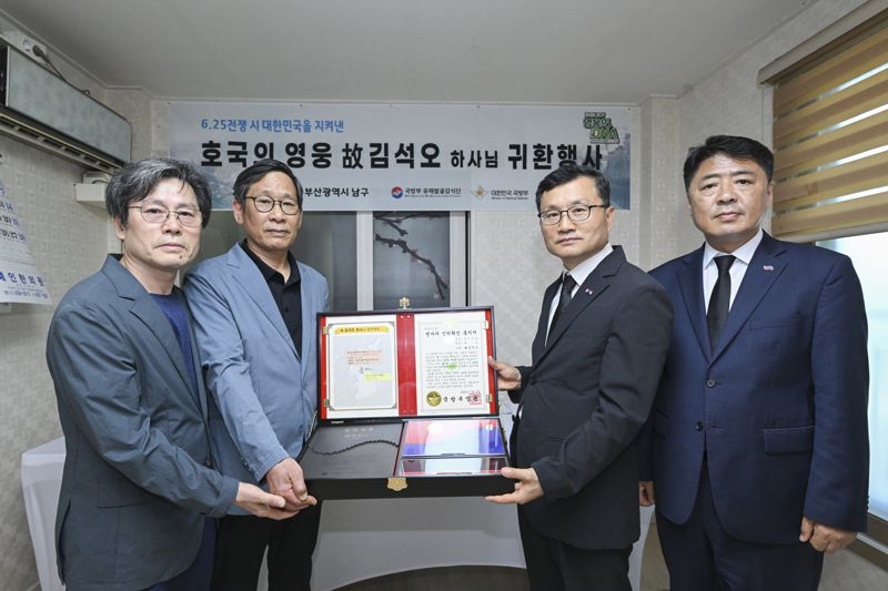 '호국의 얼' 함을 전달하고 기념사진을 촬영하고 있는 고 김석오 하사의 유가족과 이근원 국방부유해발굴감식단장(왼쪽에서 세 번째), 오은택 부산광역시 남구청장(맨 오른쪽). 국유단 제공
