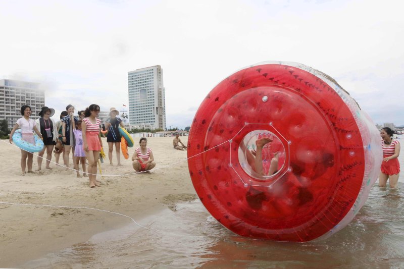 [원산=AP/뉴시스] 지난 2일 북한 강원도 원산의 원산-갈마 해안관광지구에서 사람들이 대형 물풍선 속에서 구르며 물놀이를 즐기는 남성들을 바라보고 있다. 북한 노동신문은 갈마관광지구 개장을 알리며 "세상에 없는 황홀한 관광 명소"라고 선전했다. 원산 명사십리 해변 일대에 조성된 관광지구 개발은 북한이 11년간 공들인 숙원사업으로 알려져 있다. 2025.07.04.