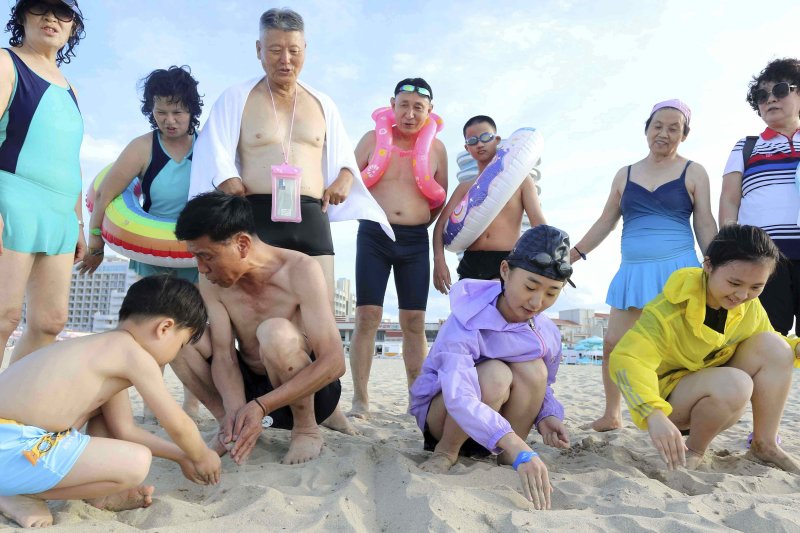 [원산=AP/뉴시스] 지난 2일 북한 강원도 원산의 원산-갈마 해안관광지구에서 어린이들이 모래사장에 '우리 조국'이라고 쓰는 모습을 어른들이 지켜보고 있다. 북한 노동신문은 갈마관광지구 개장 소식을 알리며 "세상에 없는 황홀한 관광 명소"라고 선전했다. 원산 명사십리 해변 일대에 지어진 관광지구 개발은 북한이 11년간 공들인 숙원사업으로 알려져 있다. 2025.07.04.