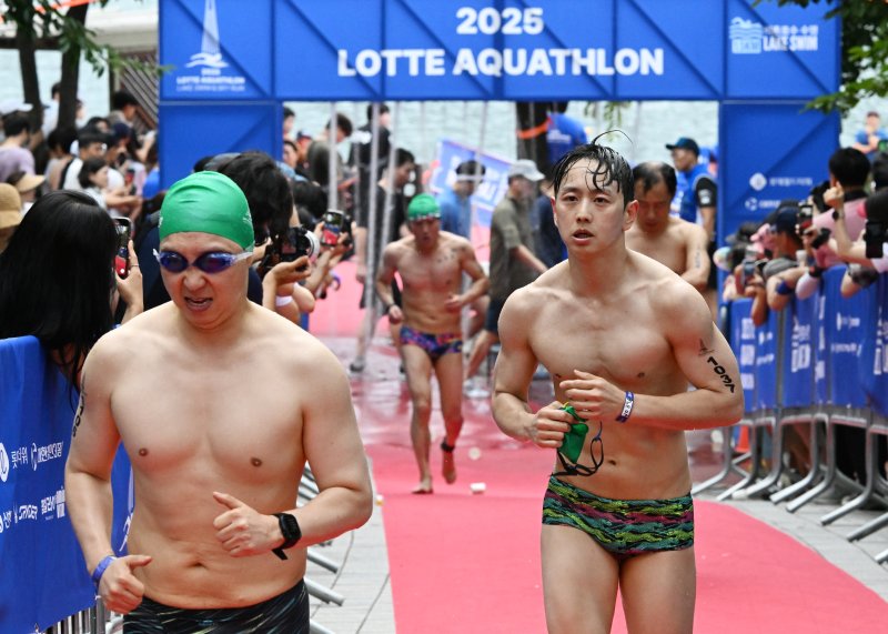 [서울=뉴시스] 김근수 기자 = 6일 오전 서울 송파구 롯데월드타워 일대에서 열린 '2025 롯데 아쿠아슬론'에서 참가자들이 수영을 마친 뒤 코스 이동을 하고 있다. 철인 3종 경기에서 사이클론을 제외한 오픈워터 수영과 마라톤을 함께 겨루는 '2024 롯데 아쿠아슬론'은 석촌호수 두 바퀴(총 1.5Km)를 완영 후, 롯데월드타워 1층부터 123층까지 2,917개의 계단을 오르는 수직 마라톤 스카이런(SKY RUN)으로 진행됐다.(공동취재) 2025.07.06. photo@newsis.com