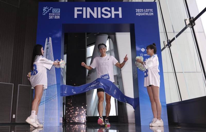 [서울=뉴시스] 김근수 기자 = 6일 오전 서울 송파구 롯데월드타워 일대에서 열린 '2025 롯데 아쿠아슬론'에서 참가자가 결승점을 통과하고 있다. 철인 3종 경기에서 사이클론을 제외한 오픈워터 수영과 마라톤을 함께 겨루는 '2025 롯데 아쿠아슬론'은 석촌호수 두 바퀴(총 1.5Km)를 완영 후, 롯데월드타워 1층부터 123층까지 2,917개의 계단을 오르는 수직 마라톤 스카이런(SKY RUN)으로 진행됐다. 2025.07.06. ks@newsis.com