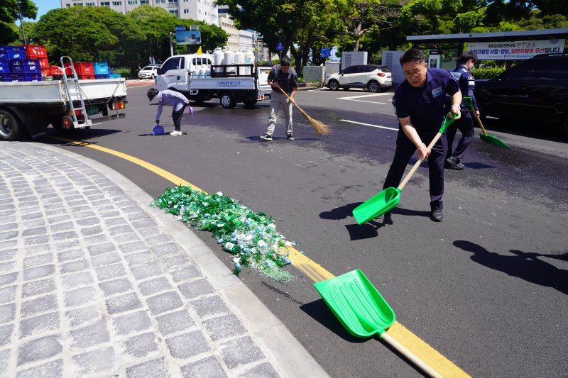 [제주=뉴시스] 7일 오전 10시50분께 제주시 연동 신제주로터리에서 청원경찰들이 도로에 흩어진 주류 박스와 깨진 소주병들을 수거하고 있다. (사진=제주도 제공) 2025.07.07. photo@newsis.com