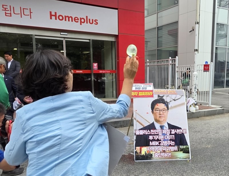 마트 노동자들이 2일 천안시 동남구 홈플러스 천안점 앞에서 열린 폐점 반대 기자회견에서 김병주 MBK파트너스 회장을 규탄하며 얼굴 사진에 물풍선을 던지고 있다. 2025.6.2/뉴스1 ⓒ News1 이시우 기자