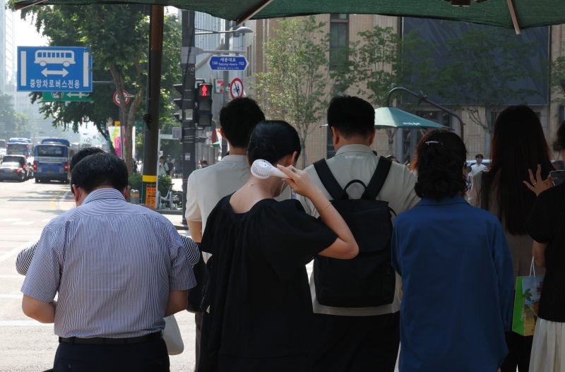[서울=뉴시스] 최진석 기자 = 폭염이 이어지고 있는 8일 서울 세종대로사거리 인근에서 한 시민이 그늘막 아래서 손 선풍기를 틀고 더위를 식히고 있다. 2025.07.08. myjs@newsis.com