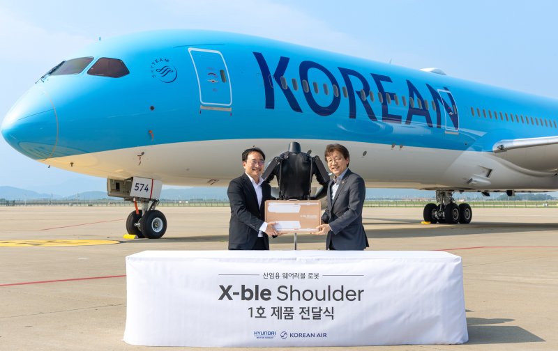 8일 인천 중구 소재 대한항공 항공기 정비고에서 현대자동차·기아가 개발한 산업용 착용로봇 '엑스블 숄더'(X-ble Shoulder) 1호 인도식이 열렸다. (왼쪽부터) 현동진 현대차·기아 로보틱스랩 상무, 정현보 대한항공 항공우주사업본부 상무가 기념 사진을 촬영한 모습(현대차·기아 제공). 2025.07.08.