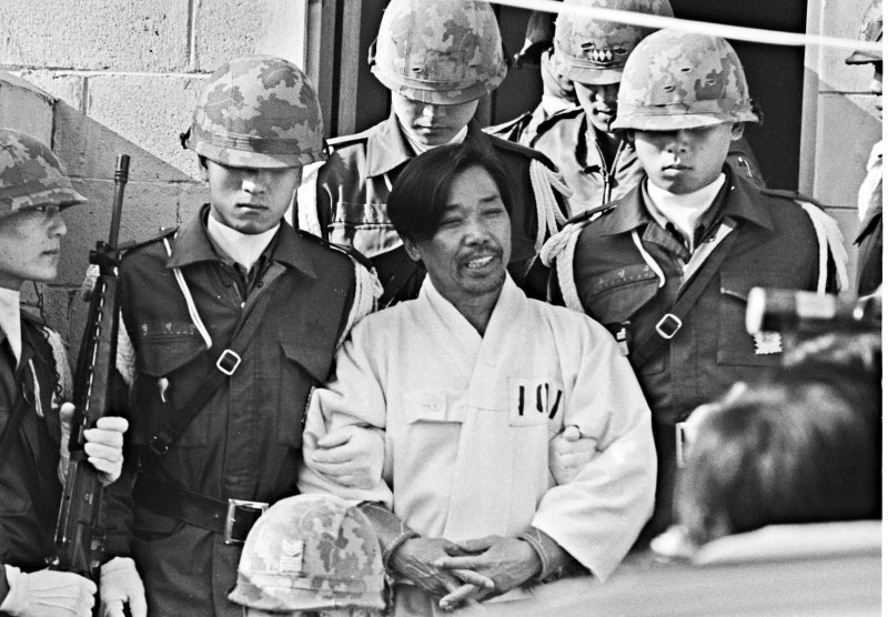 [서울=뉴시스]'10·26 사태'로 사형된 고(故) 김재규 전 중앙정보부장의 재심이 오늘 시작된다. 사형 집행 45년, 재심 청구 5년 만이다. 사진은 박정희 대통령 시해사건 관련자 김재규(전 중앙정보부장) 피고인이 육군본부 계엄 보통군법회의(재판장 김영선 중장)에서 선고공판을 받기 위해 포승에 묶여 걸어오며 웃고 있다. 이날 김재규, 김계원, 박선호, 박흥주, 이기주, 유성옥, 김태원 등 7명은 내란목적살인죄가 적용돼 사형을 선고 받은 모습. <1979년 12월20일, 권주훈>