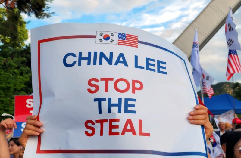 15일 오후 서울대 정문 앞에서 열린 모스 탄 교수의 특별강연 참석한 한 시민이 'CHINA LEE, STOP THE STEAL(차이나 리, 스탑더 스틸)'라는 문구가 적힌 손팻말을 들고 있다.