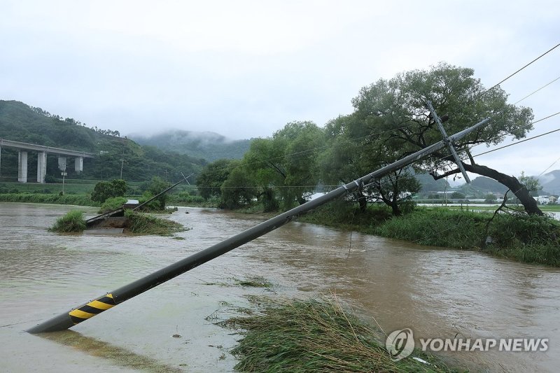 도로와 함께 위태롭게 내려앉은 전봇대 (출처=연합뉴스)
