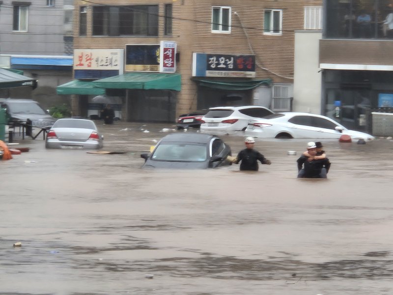 7월 17일 대구시 북구 노곡동 일대가 침수돼 상가와 차량이 물이 잠겼다. 주민이 물길을 헤치고 걸어가고 있다. 뉴스1