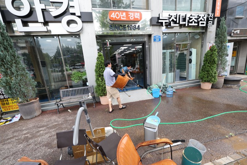 18일 광주 북구 용봉동 전남대 후문 일대가 전날 내린 폭우로 침수돼 한 안경상가의 상인이 물에 젖은 의자를 닦은 후 옮기고 있다. 2025.7.18/뉴스1 ⓒ News1 박지현 기자