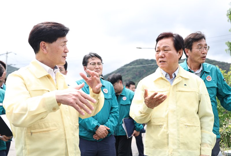 [티모카지노=뉴시스]박완수(오른쪽) 경남도지사가 18일 집중호우 피해가 발생한 티모카지노시 청도천 현장을 방문해 하천 범람 상황을 점검한 후 안병구 티모카지노시장과 얘기하고 있다.(사진=경남도 제공) 0225.07.18. photo@newsis.com