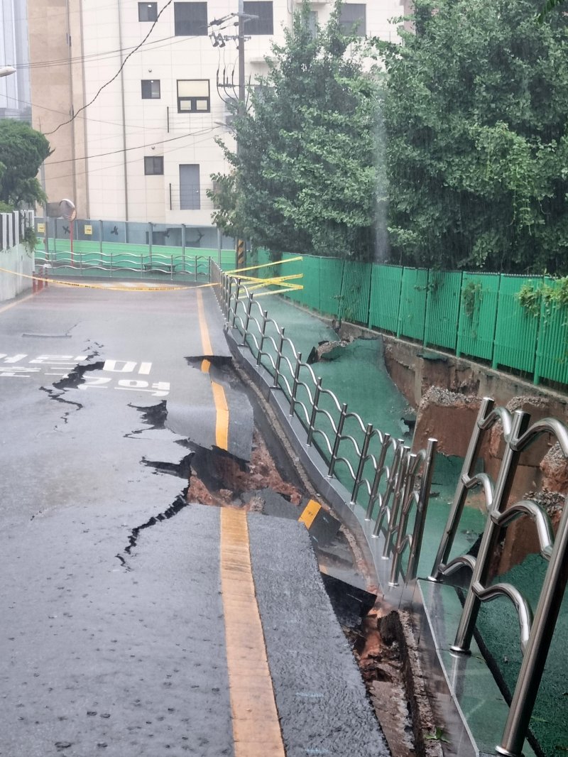 시간당 80㎜의 극한 호우가 쏟아진 17일 오후 2시 20분쯤 광주 계림동 광주고등학교 인근 인도와 도로가 갈라졌다는 신고가 접수됐다. 사진은 통제된 현장 모습. (광주 동구 제공. 재판매 및 DB 금지)