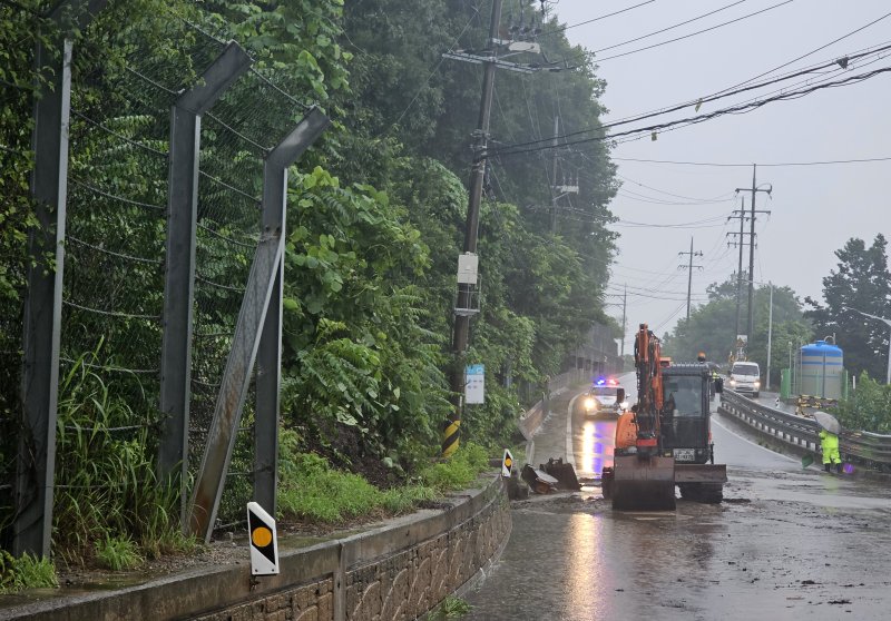 20일 오전 춘천시 신북읍 용산리 피암터널 인근 도로에 토사가 유실돼 춘천시 관계자들이 중장비를 동원해 치우고 있다. 연합뉴스