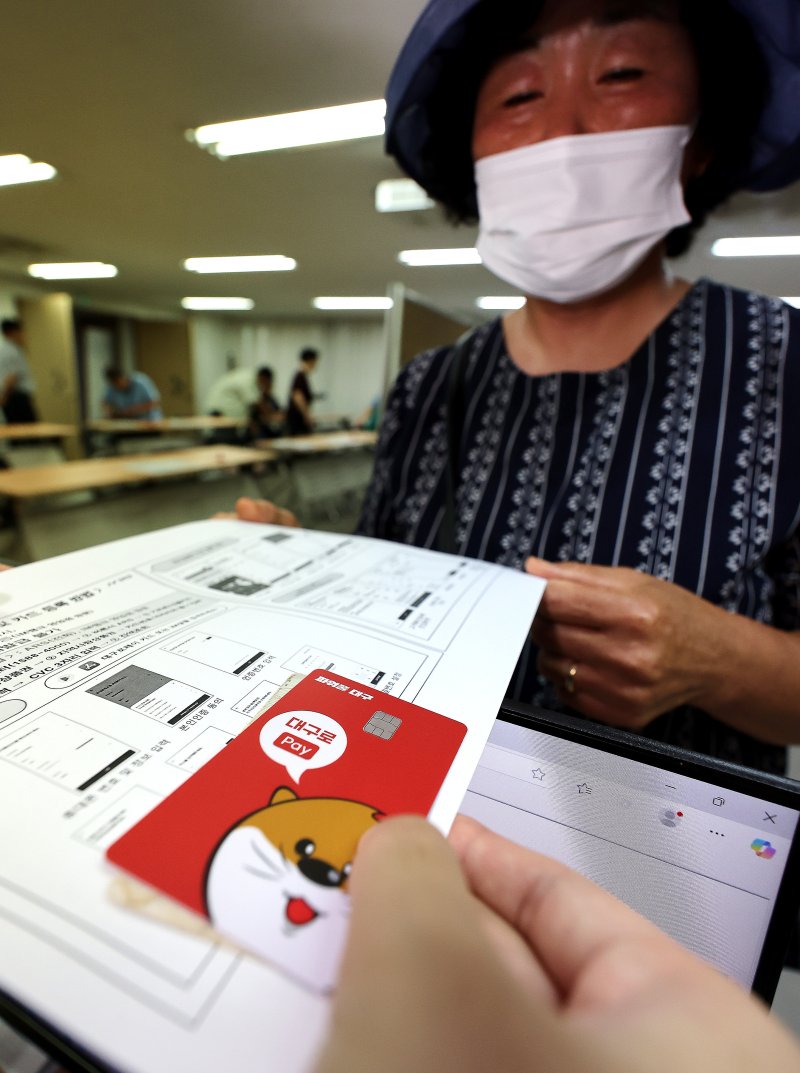 [대구=뉴시스] 이무열 기자 = 민생회복 소비쿠폰 신청 첫날인 21일 대구 중구 대신동행정복지센터에서 한 시민이 선불카드를 수령받고 있다. 2025.07.21. lmy@newsis.com