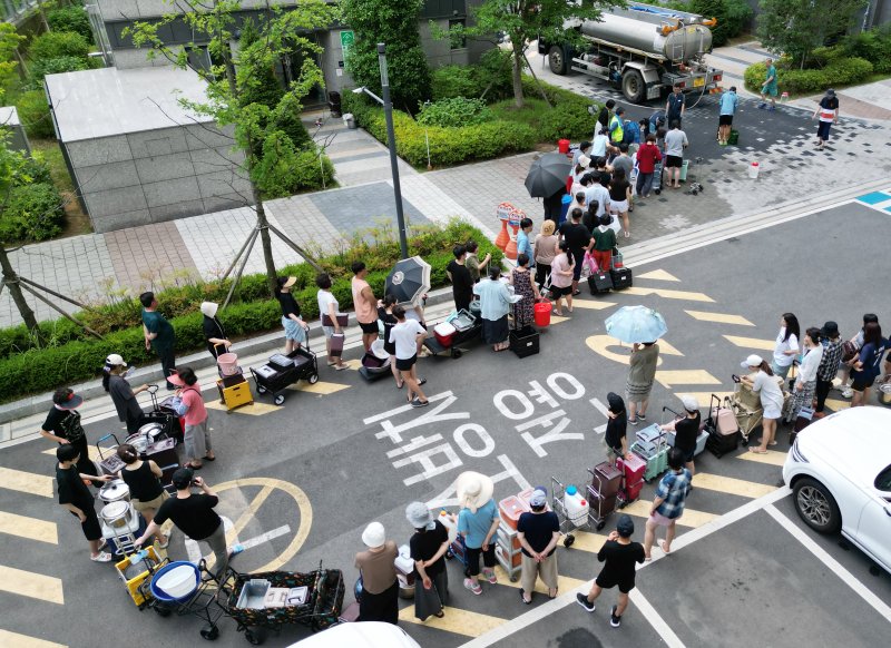 지난 21일 울산 울주군 언양읍 한 아파트 주민들이 살수차에서 물을 받아 가기 위해 줄을 서 있다. 울산시 상수도사업본부에 따르면 지난 19일 내린 호우로 상수도 송수관로가 파손된 영향으로 지난 20일 오전부터 울주군 6개 읍·면 지역에 수돗물 공급이 중단됐다. 연합뉴스