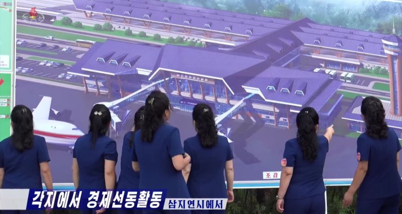 지난 18일 조선중앙TV 보도에는 선전음악단이 '삼지연국제비행장'을 묘사한 3D 렌더링 디스플레이를 가리키고 있는 모습이 담겼다.(조선중앙TV 갈무리).