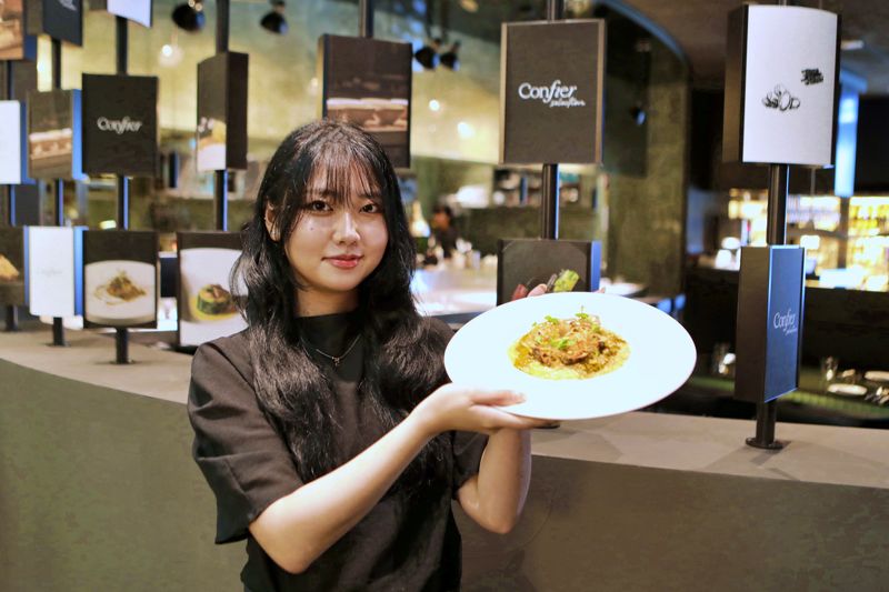 잠실 롯데월드몰 6층 콘피에르 셀렉션에서 모델이 음식을 소개하고 있다. 롯데백화점 제공