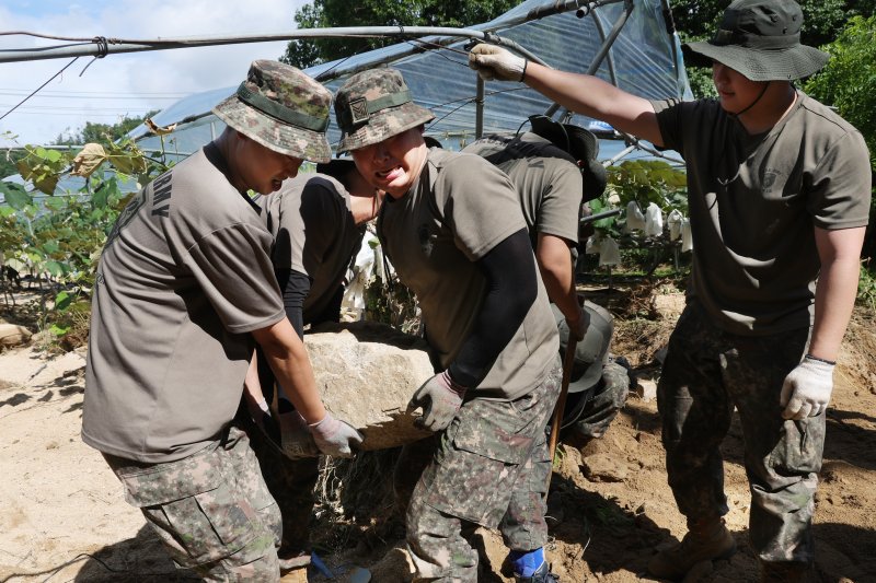 23일 경기도 가평군 상면 수해 지역에서 육군 수도기계화보병사단 혜산진여단 장병들이 중장비 진입이 불가능한 포도밭을 덮친 암반석을 치우고 있다. 연합뉴스