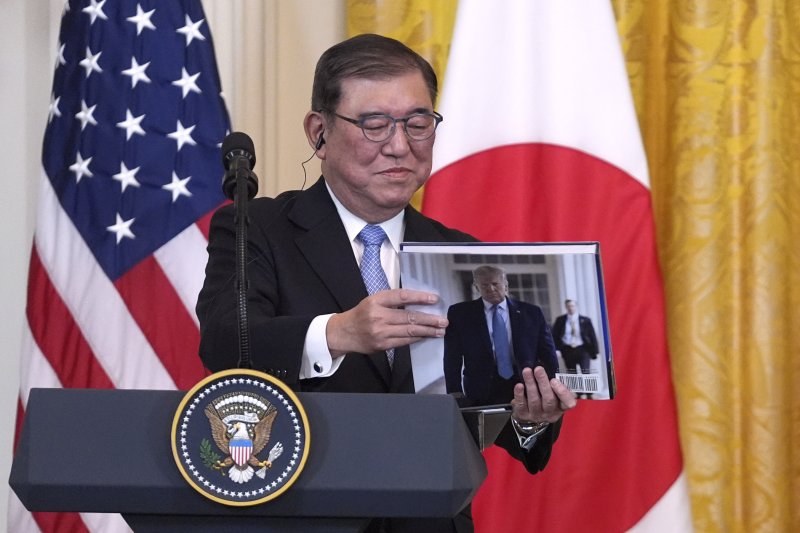 [워싱턴=AP/뉴시스] 이시바 시게루 일본 총리가 7일(현지 시간) 미국 백악관에서 열린 정상회담 후 공동 기자회견에서 도널드 트럼프 미국 대통령이 선물한 책을 들여다보고 있다. 2025.02.08.