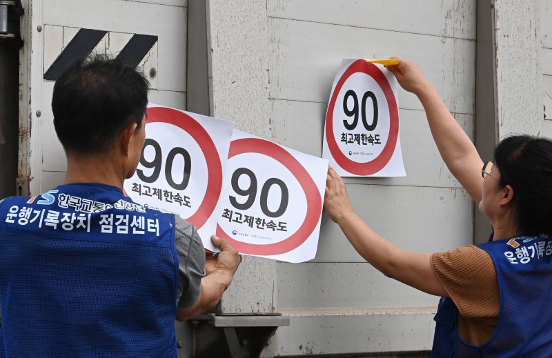[화성=뉴시스] 김종택 기자 = 23일 경기 화성시 한 화물차 운행기록장치(DTG)점검센터에서 관계자들이 화물차 후면에 최고 제한속도 스티커를 부착하고 있다. 국토교통부와 한국교통안전공단(TS)은 오늘부터 총중량 3.5t(톤)을 초과하는 화물차를 대상으로 ‘최고 제한속도(90㎞/h) 스티커’를 부착하는 시범사업을 실시했다. 2025.07.23. jtk@newsis.com