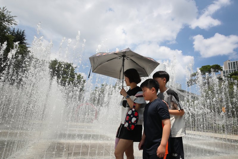 오전부터 폭염이 시작된 23일 대구 서구 서부도서관 앞 평리공원에서 양산을 쓴 가족이 바닥분수 물줄기 옆을 지나고 있다. 2025.7.23/뉴스1 ⓒ News1 공정식 기자