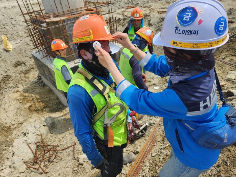 [서울=뉴시스] DL이앤씨 현장 안전보건관리자가 근로자의 체온을 측정하고 건강상태를 확인하고 있다.