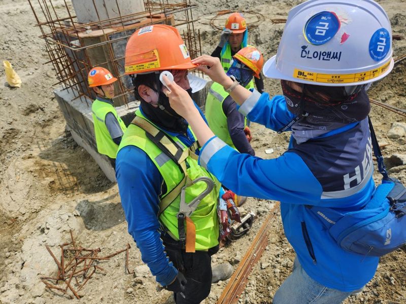 DL이앤씨 현장 안전보건관리자가 근로자의 체온을 측정하고 건강상태를 확인하고 있다. DL이앤씨 제공