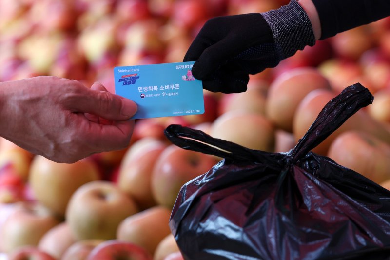 [서울=뉴시스] 조성우 기자 = 소비자심리지수가 4년 만에 최고치를 기록한 23일 서울 시내의 한 전통시장에서 한 시민이 민생회복 소비쿠폰을 이용해 과일을 구매하고 있다. 2025.07.23. xconfind@newsis.com