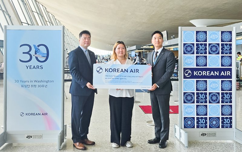 25일 미국 워싱턴DC 덜레스 국제공항에서 인천으로 향하는 대한항공 KE094편 탑승객 중 30번째로 수속한 승객 이윤주씨와 이병훈 대한항공 미동부지점장(왼쪽), 석인학 워싱턴공항지점장(오른쪽)이 인천~워싱턴 왕복 항공권을 들고 기념사진을 촬영했다(대한항공 제공). 2025.07.25.