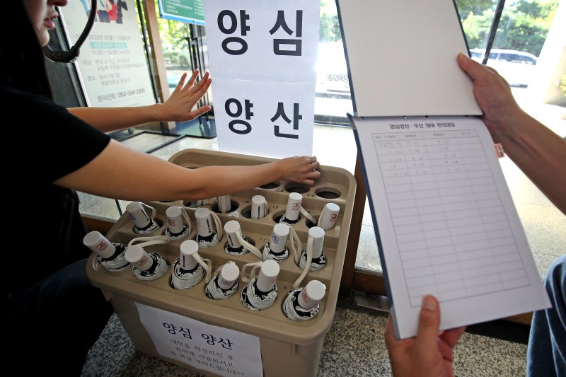 폭염이 이어진 28일 오전 대구 달서구청 직원들이 민원실에서 양산꽂이 앞에 '양심양산' 안내문을 붙이고 있다. '양심에 맡기자'는 취지로 빌려주는 이 양산은 이용자가 관리대장을 작성하지 않는 경우가 많아 회수율이 낮다. 2025.7.28/뉴스1 ⓒ News1 공정식 기자