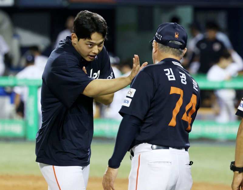 [서울=뉴시스] 홍효식 기자 = 22일 서울 송파구 잠실야구장에서 열린 2025 KBO리그 한화 이글스와 두산 베어스의 경기, 2-1로 승리한 한화 선발투수 문동주와 김경문 감독이 하이파이브 하고 있다.이번 승리로 한화는 단일 시즌 두 번째 10연승을 달성하며, 구단 최초 기록을 세웠다. 2025.07.22. yesphoto@newsis.com