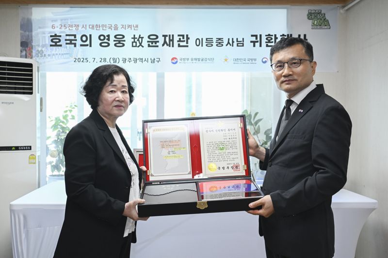 고 윤재관 이등중사(현 병장)의 유가족(딸) 윤금순 씨(왼쪽·74세)에게 '호굴의 얼 함'를 전달하는 이근원 국방부유해발굴감식단장(오른쪽). 국방부 제공