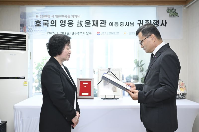 고 윤재관 이등중사(현 병장)의 유가족(딸) 윤금순 씨(왼쪽·74세)에게 '전사자 신원확인 통지서'를 전달하는 이근원 국방부유해발굴감식단장(오른쪽). 국방부 제공