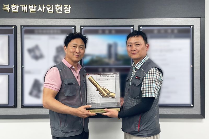 이승환 주택안전팀 상무(왼쪽)가 현장소장에게 '안전 바통'을 전달하고 있다. 롯데건설 제공