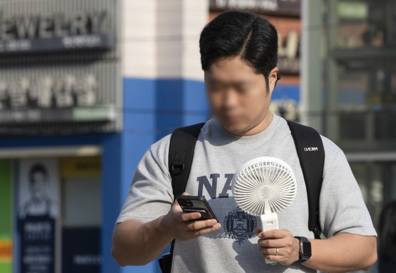 [서울=뉴시스] 김근수 기자 = 전국에 기록적인 폭염이 이어진 30일 오전 서울 서초구 고속버스터미널 인근에서 한 시민이 손풍기를 쐬며 출근길에 나서고 있다. 2025.07.30. ks@newsis.com