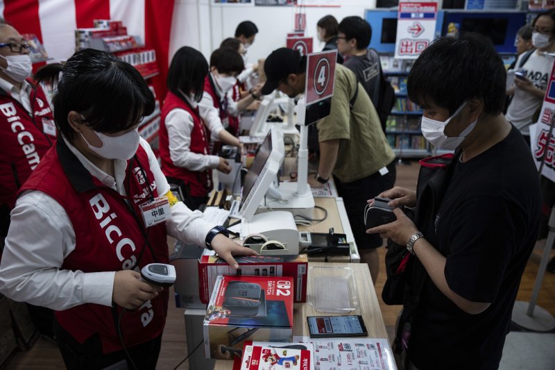 [도쿄=AP/뉴시스] 5일(현지 시간) 일본 도쿄의 한 전자제품 판매점에서 한 손님이 닌텐도의 차세대 콘솔 ‘스위치2’를 구매하고 있다. 이날 공식 출시된 ‘스위치2’는 전작과 많은 유사점을 지니면서도, 더 커진 화면과 향상된 그래픽을 갖춘 것이 특징이다. 2025.06.05.