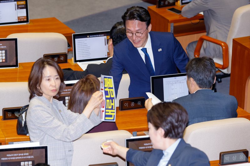 김민석 신임 국무총리가 4일 국민의힘 의원석으로 가 인사하는 가운데 최수진 당시 원내대변인이 '특활비도 내로남불'이라고 적힌 피켓을 의원석에 붙이고 있다. 2025.7.4/뉴스1 ⓒ News1 안은나 기자