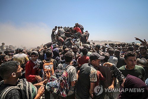 식량 배급소 인근에서 밀가루를 가져가려고 분투하는 가자 주민들 (출처=연합뉴스)