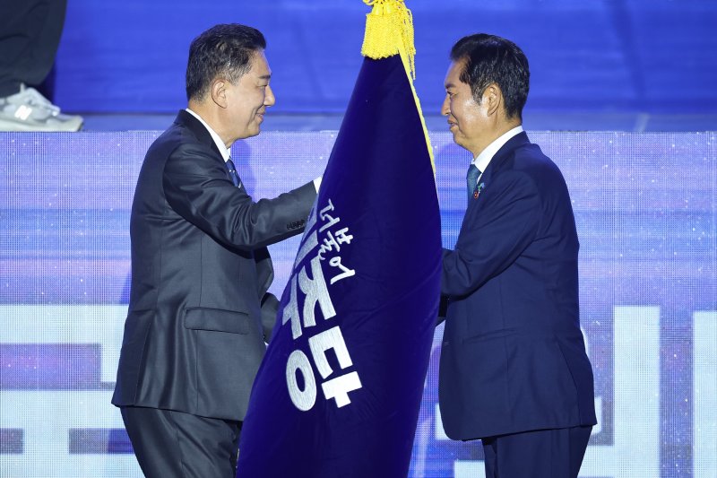 정청래 더불어민주당 신임 당대표가 2일 경기 고양시 킨텍스에서 열린 제2차 임시전국당원대회에서 김병기 원내대표로 부터 당기를 이양받고 있다. 2025.8.2/뉴스1 ⓒ News1 유승관 기자