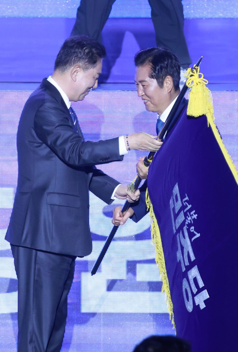 [고양=뉴시스] 고승민 기자 = 정청래 신임 더불어민주당 대표가 2일 경기 고양 킨텍스에서 열린 더불어민주당 제2차 임시전국당원대회에서 김병기 직무대행 겸 원내대표로부터 당기를 이양받고 있다. 2025.08.02. kkssmm99@newsis.com