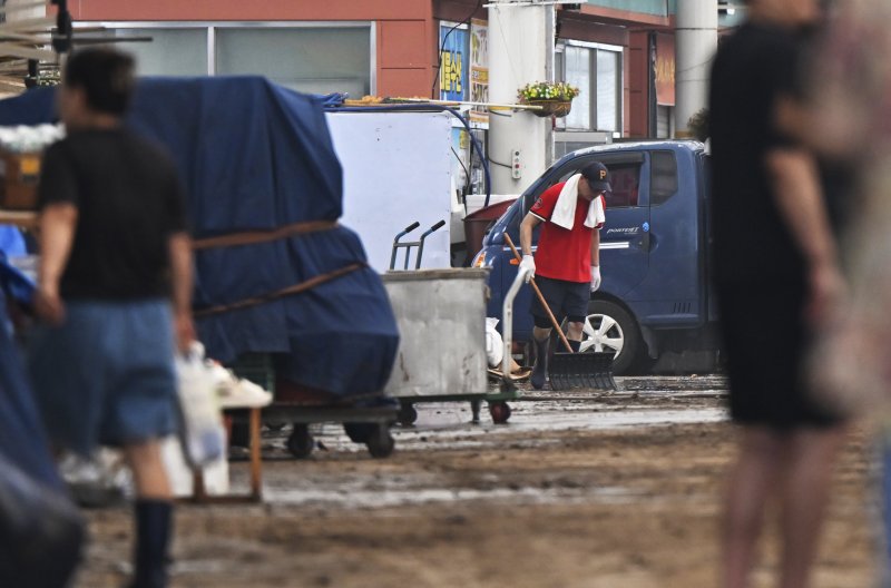 [함평=뉴시스] 박기웅 기자 = 4일 오전 전남 함평군 함평읍 함평천지전통시장 상인들이 흙탕물로 뒤덮인 거리를 청소하고 있다. 함평에는 전날 많은 비가 내리면서 주택 50가구와 상가 46곳이 침수된 것으로 잠정 집계됐다. 2025.08.04. pboxer@newsis.com