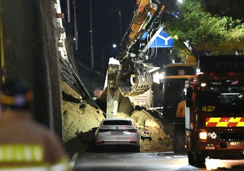 [오산=뉴시스] 김종택 기자 = 수도권 등 중부지역에 호우주의보가 발효된 16일 오후 경기 오산시 가장교차로 고가도로 옹벽이 무너져 소방관들이 매몰된 차량을 구조작업하고 있다. 2025.07.16. jtk@newsis.com