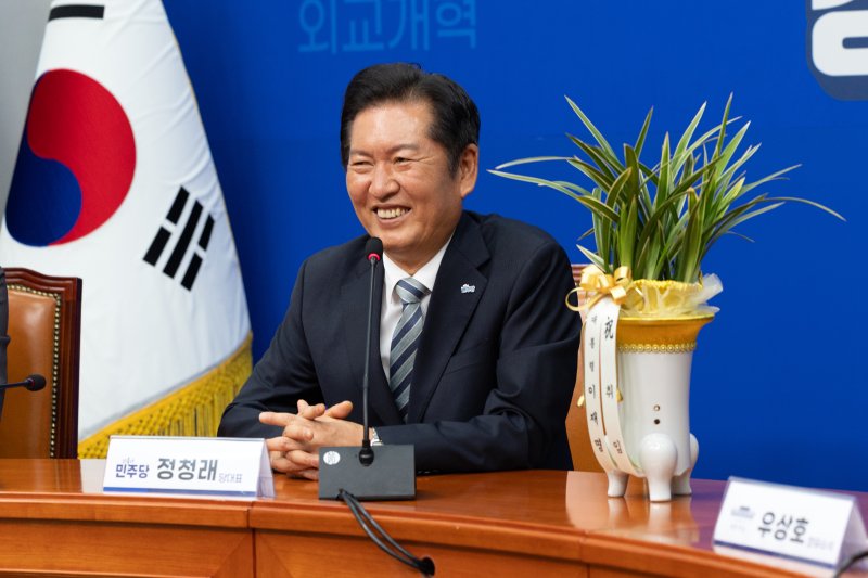 정청래 더불어민주당 신임 대표가 4일 오후 서울 여의도 국회에서 우상호 대통령실 정무수석으로부터 대통령 축하 난을 받고 미소 짓고 있다. 2025.8.4/뉴스1 ⓒ News1 이승배 기자