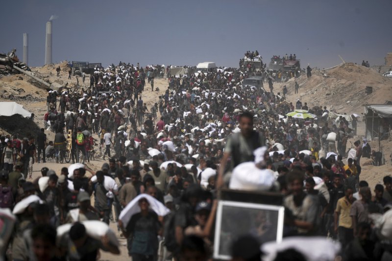 [베이트 라히야=AP/뉴시스] 1일(현지 시간) 가자지구 북부 베이트 라히야 외곽에서 팔레스타인 주민들이 가자시티로 향하던 인도적 물품 수송 트럭에서 내린 밀가루 자루를 나르고 있다. 2025.08.02.